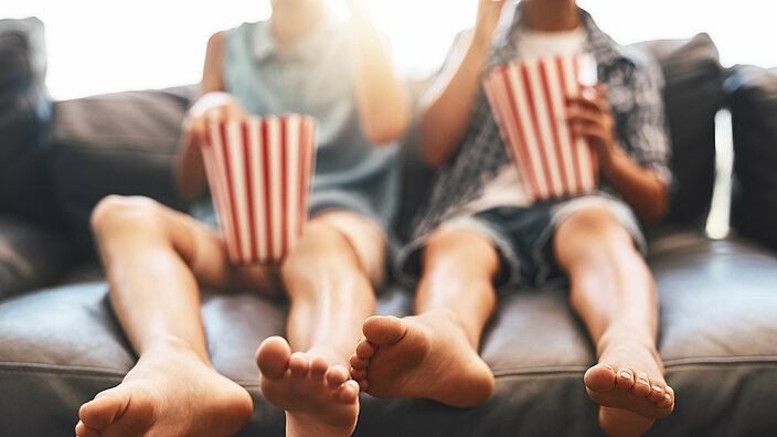 Its movie time. Cropped shot of a brother and sister eating popcorn and watching movies on the sofa at home.