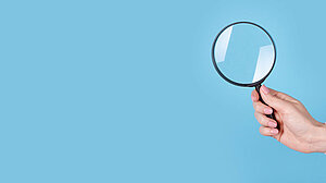 Magnifying glass in hand on a blue background, copy space template, banner.