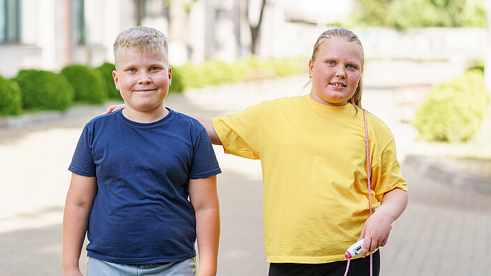 Fat boy and girl posing outdoors during a fitness class.