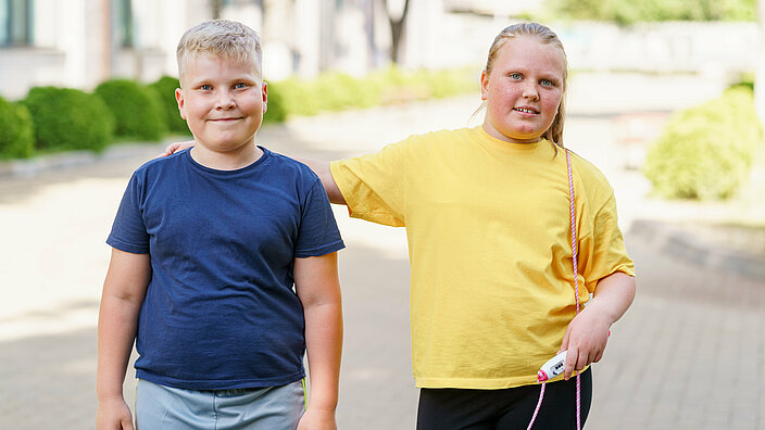 Fat boy and girl posing outdoors during a fitness class.