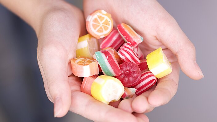 KInderhände halten bunte und vielfältige Süßwaren, u.a. Bonbons.