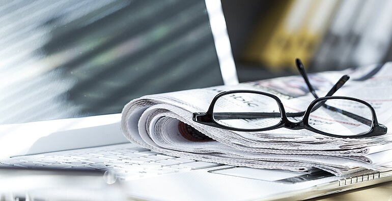 Laptop und Zeitung auf einem Schreibtisch