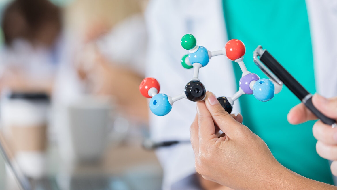 Person zeigt Modell einer chemischen Verbindung 